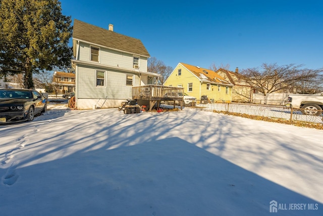 snow covered house featuring a wooden deck