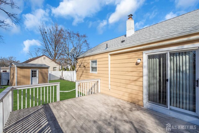 wooden terrace with a storage unit and a lawn