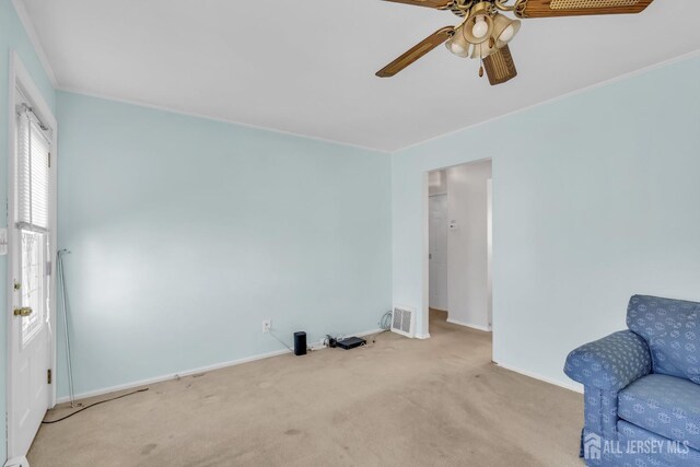 living area with light carpet, ceiling fan, and ornamental molding