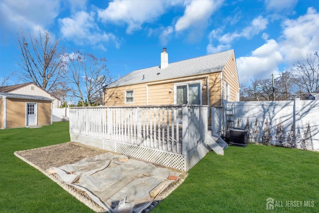 back of property with a lawn, a deck, an outbuilding, and central air condition unit