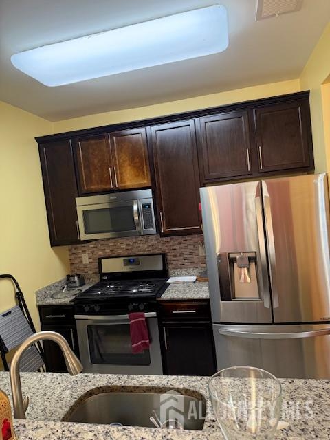 437 NE Micali Way S, Plainfield, NJ 07080 - kitchen featuring appliances with stainless steel finishes, light stone countertops, backsplash, and dark brown cabinets