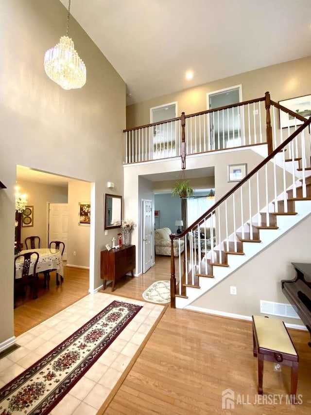 57 Yorktown Rd, South Brunswick, NJ 08852 - foyer entrance with stairway, a towering ceiling, a chandelier, and wood finished floors