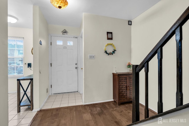 entrance foyer with stairway, light wood-type flooring, and baseboards