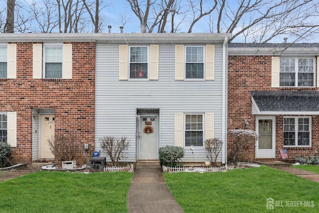 townhome / multi-family property with brick siding and a front yard