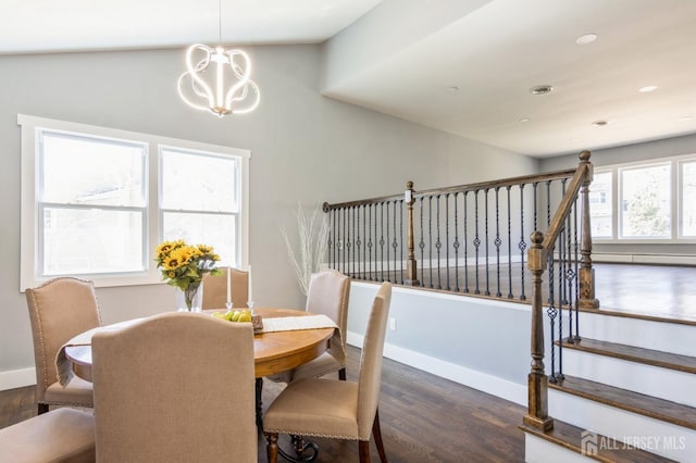 dining space with baseboards, lofted ceiling, wood finished floors, and a chandelier