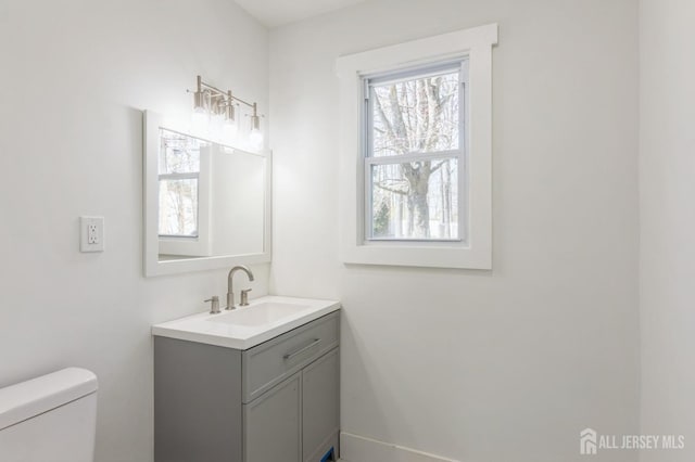 bathroom with toilet, baseboards, and vanity