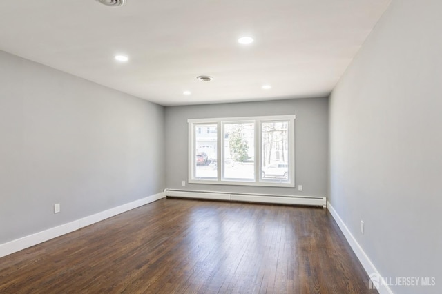 spare room featuring recessed lighting, baseboards, a baseboard heating unit, and dark wood-style floors