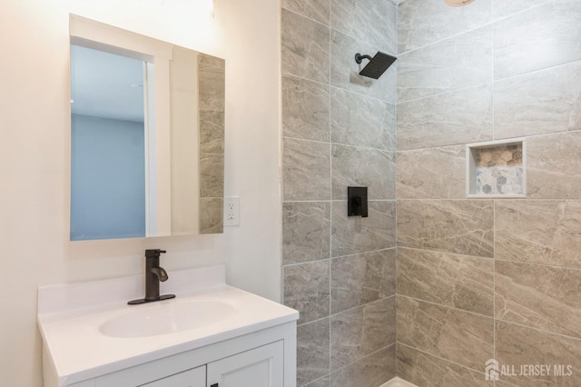 full bathroom featuring vanity and tiled shower