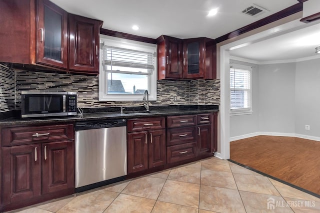 kitchen with stainless steel appliances, sink, light tile patterned floors, dark stone counters, and crown molding