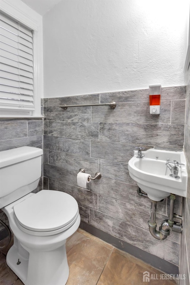 bathroom featuring tile walls, sink, and toilet