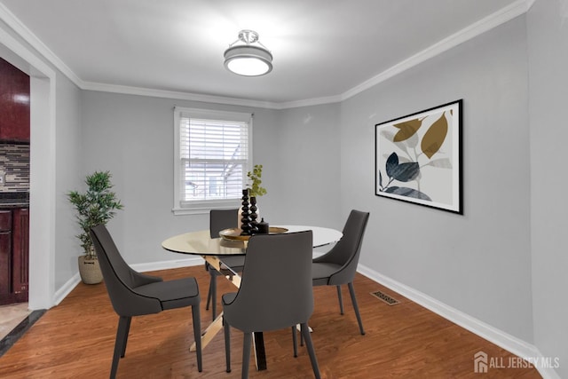 dining space with light wood-type flooring and ornamental molding