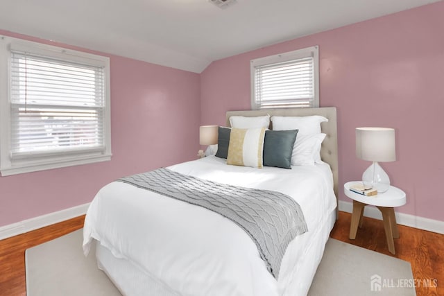 bedroom featuring hardwood / wood-style floors, multiple windows, and lofted ceiling