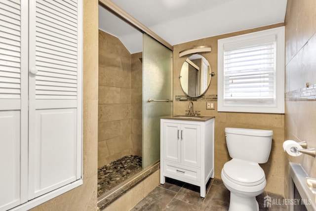 bathroom with tile walls, vanity, toilet, and walk in shower