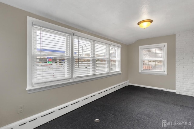 unfurnished room with baseboard heating, lofted ceiling, and dark carpet