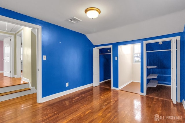 unfurnished bedroom featuring a closet, vaulted ceiling, and dark hardwood / wood-style floors