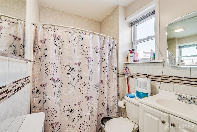 bathroom with tile walls, vanity, plenty of natural light, and walk in shower