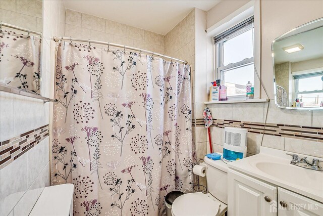 bathroom with tile walls, vanity, curtained shower, and toilet