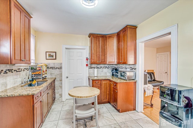 kitchen with tile walls, sink, light stone countertops, and light tile patterned flooring