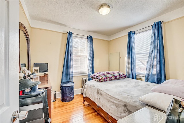 bedroom featuring multiple windows, hardwood / wood-style floors, and a textured ceiling