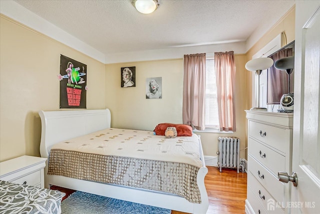 bedroom with radiator heating unit, light hardwood / wood-style floors, and a textured ceiling