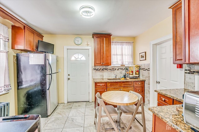 kitchen with stainless steel fridge, light stone countertops, and sink