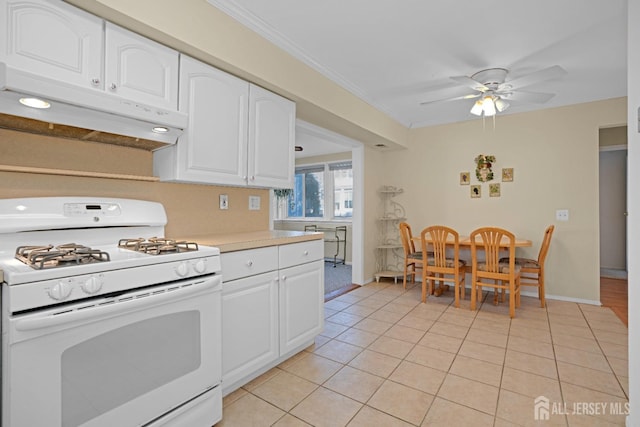 kitchen with white cabinetry, white gas stove, crown molding, and light tile patterned flooring