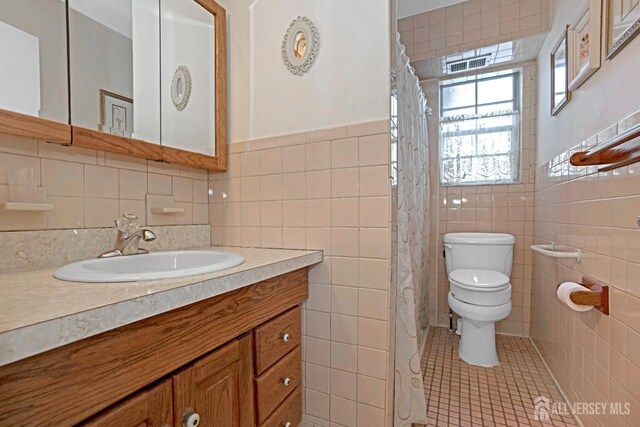 bathroom with tile patterned floors, toilet, tile walls, and vanity