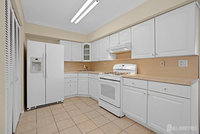 kitchen featuring sink, white cabinetry, light tile patterned floors, ornamental molding, and white appliances