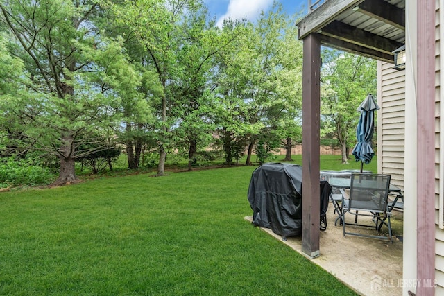 view of green lawn featuring view of wooded area