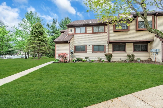 multi unit property featuring a shingled roof and a front yard