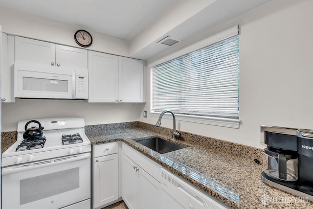 kitchen with white cabinetry, white appliances, light stone countertops, and a sink