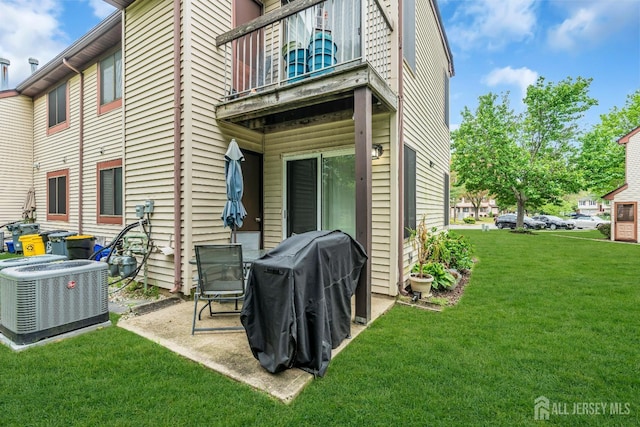 back of property with a balcony, central air condition unit, a yard, and a patio