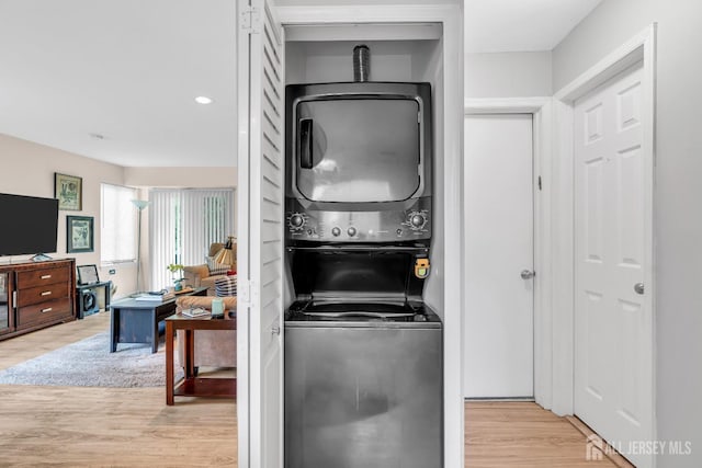 laundry room featuring stacked washing machine and dryer, light wood-style flooring, and recessed lighting