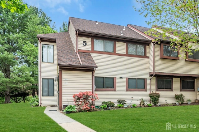 townhome / multi-family property with a shingled roof and a front yard