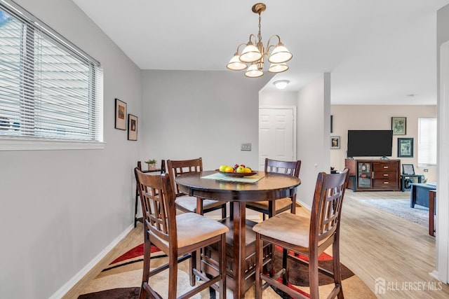 dining space with light wood finished floors, a chandelier, and baseboards