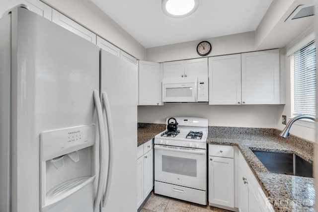 kitchen with a sink, white appliances, white cabinetry, and stone counters