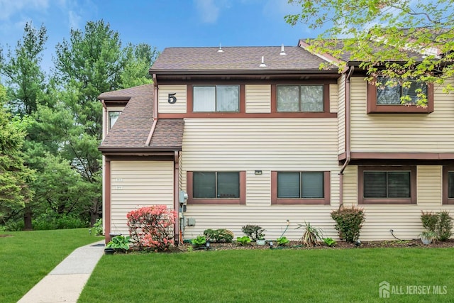 view of front of home with a front lawn and a shingled roof