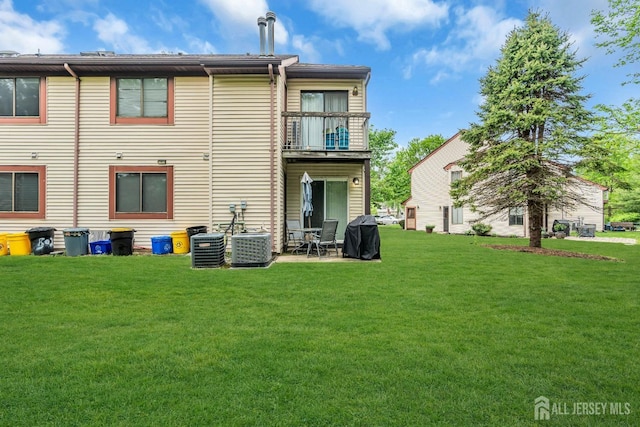 rear view of property featuring a balcony, a yard, a patio area, and central air condition unit