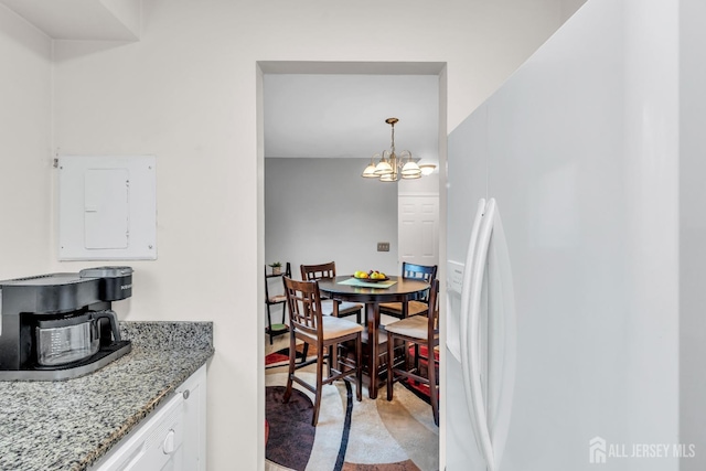 dining space featuring electric panel and a notable chandelier