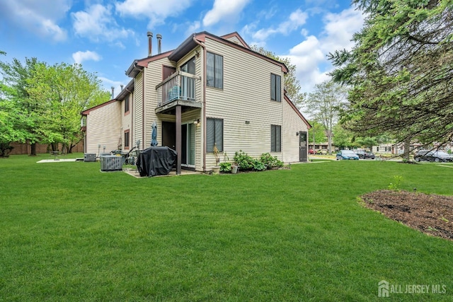 rear view of property with cooling unit, a lawn, and a balcony