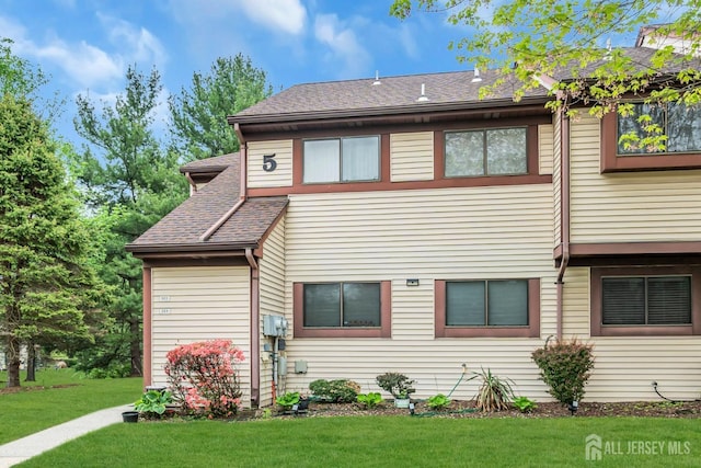 multi unit property featuring a shingled roof and a front yard