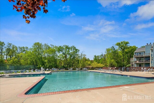 community pool with a patio and fence