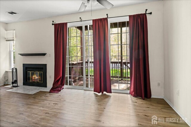 unfurnished living room with visible vents, ceiling fan, wood finished floors, and a wealth of natural light