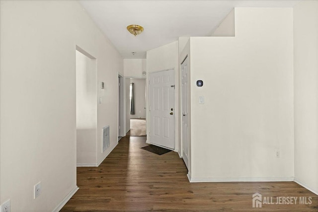corridor featuring visible vents, baseboards, and wood finished floors