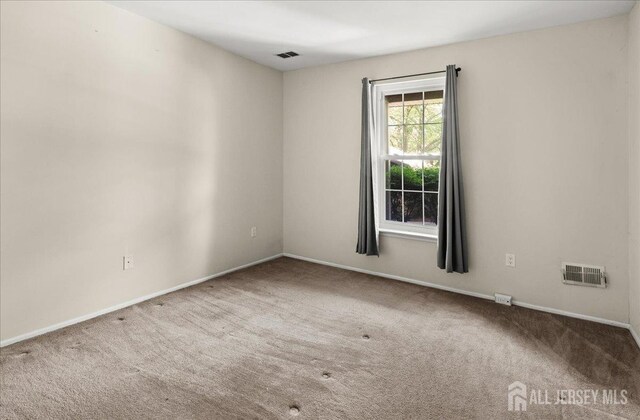 carpeted empty room featuring baseboards and visible vents