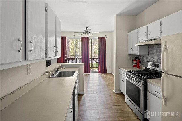kitchen featuring decorative backsplash, a sink, freestanding refrigerator, stainless steel range with gas cooktop, and under cabinet range hood