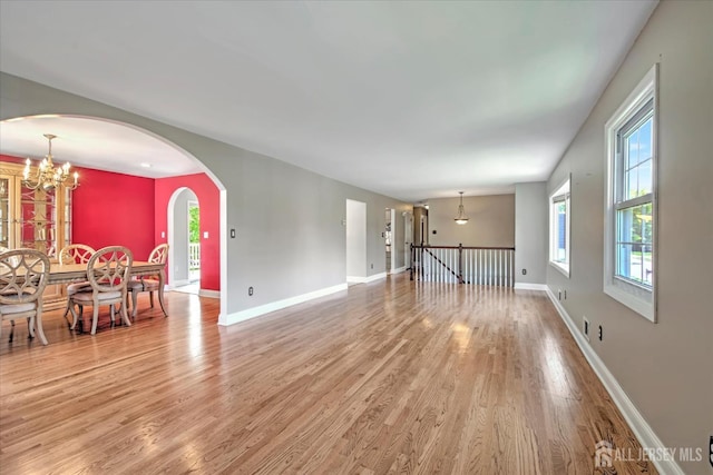 7 Mill Rd, Jamesburg, NJ 08831 - unfurnished living room featuring light wood-style floors, baseboards, a chandelier, and arched walkways