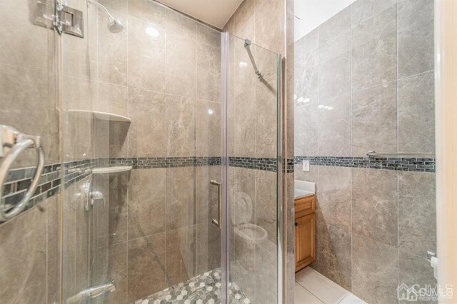 58 S Whittier St, Carteret, NJ 07008 - full bathroom featuring vanity, a stall shower, tile walls, and tile patterned floors