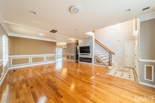 58 S Whittier St, Carteret, NJ 07008 - unfurnished living room featuring a chandelier, stairs, light wood finished floors, ornamental molding, and a large fireplace