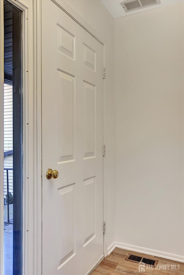 hall featuring visible vents, baseboards, and light wood-style floors